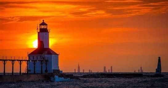 The Michigan City lighthouse at sunset, the Chicago skyline on the horizon